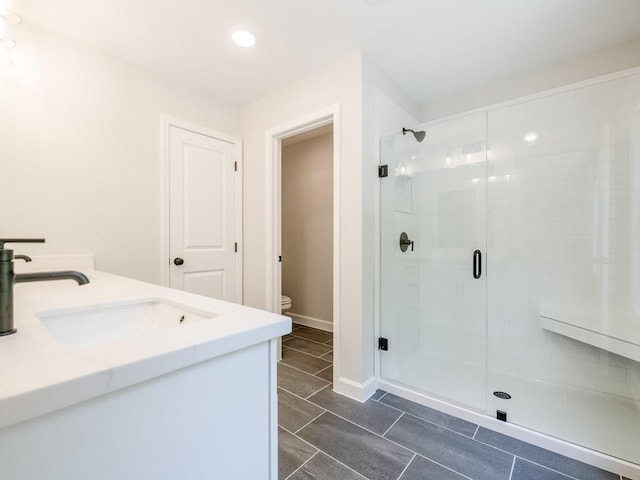 bathroom featuring an enclosed shower, vanity, and toilet