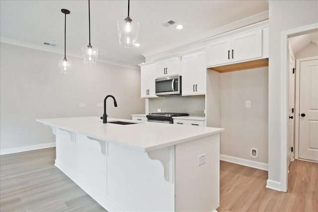 kitchen featuring an island with sink, a sink, appliances with stainless steel finishes, a kitchen bar, and crown molding