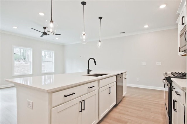 kitchen featuring light wood finished floors, stainless steel appliances, hanging light fixtures, a sink, and crown molding