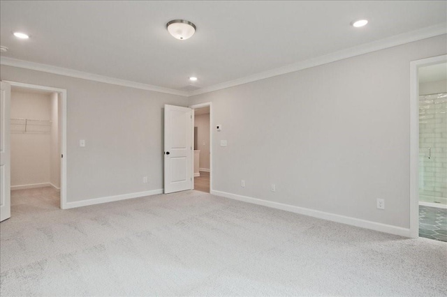 unfurnished bedroom featuring a walk in closet, carpet flooring, and baseboards