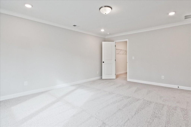 empty room featuring crown molding, recessed lighting, light colored carpet, and baseboards