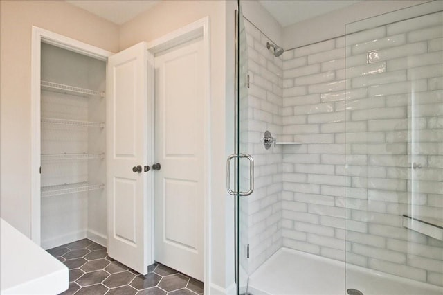 bathroom featuring tile patterned floors, a spacious closet, and a shower stall