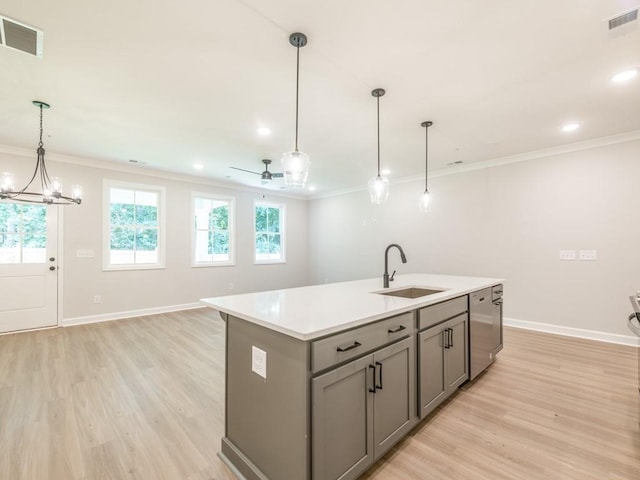 kitchen featuring a kitchen island with sink, sink, stainless steel dishwasher, gray cabinets, and decorative light fixtures