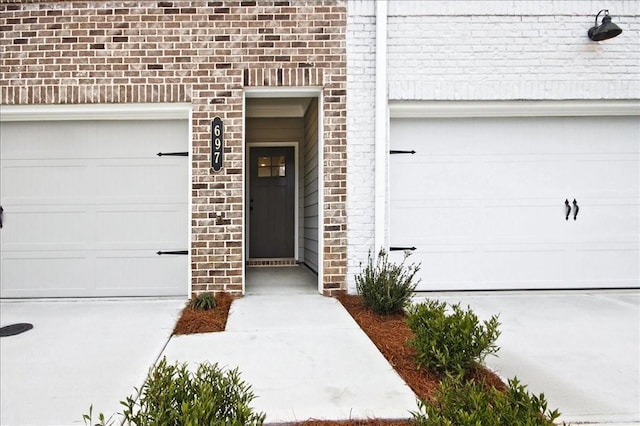 doorway to property featuring brick siding and an attached garage