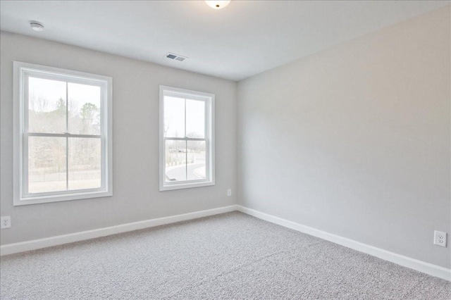 carpeted spare room featuring visible vents and baseboards