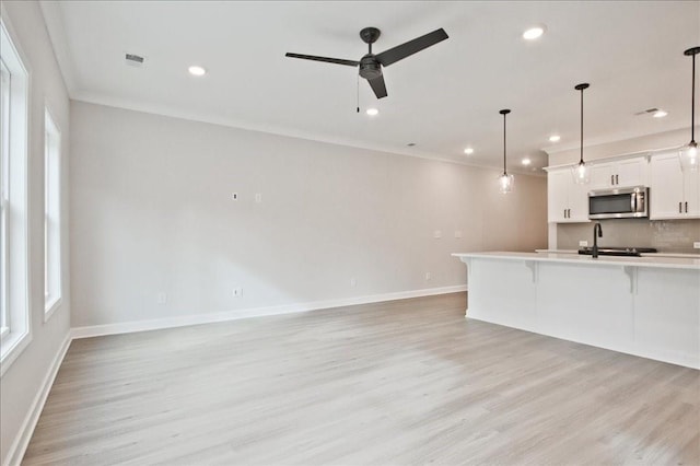 kitchen with stainless steel microwave, light wood-style flooring, a breakfast bar area, and plenty of natural light