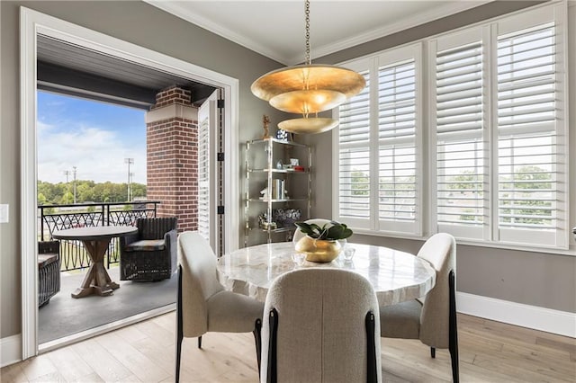 dining room with wood finished floors, baseboards, plenty of natural light, and crown molding