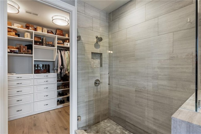 full bathroom featuring a stall shower, wood finished floors, and a spacious closet