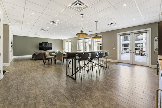 dining space with french doors, a drop ceiling, baseboards, dark wood-style flooring, and recessed lighting