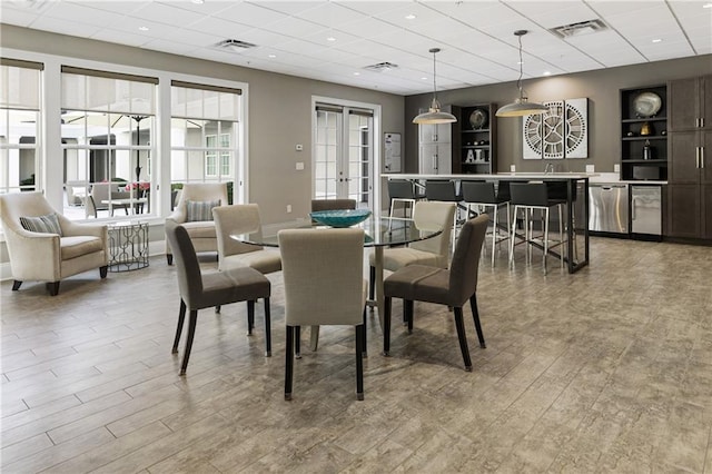 dining room with a drop ceiling, wood finished floors, and french doors