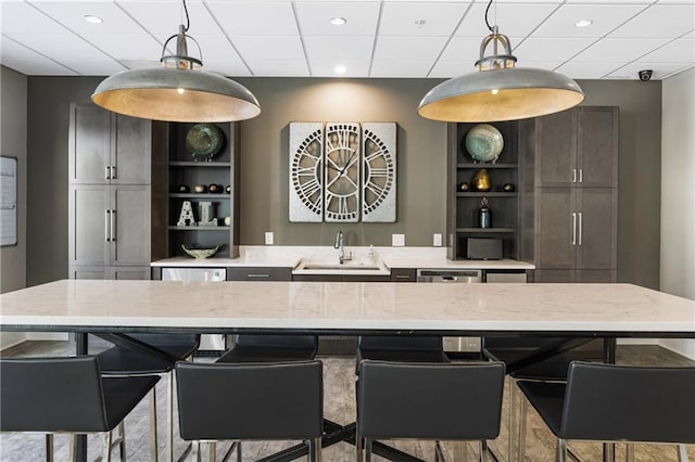 kitchen featuring open shelves, a sink, pendant lighting, light stone countertops, and recessed lighting