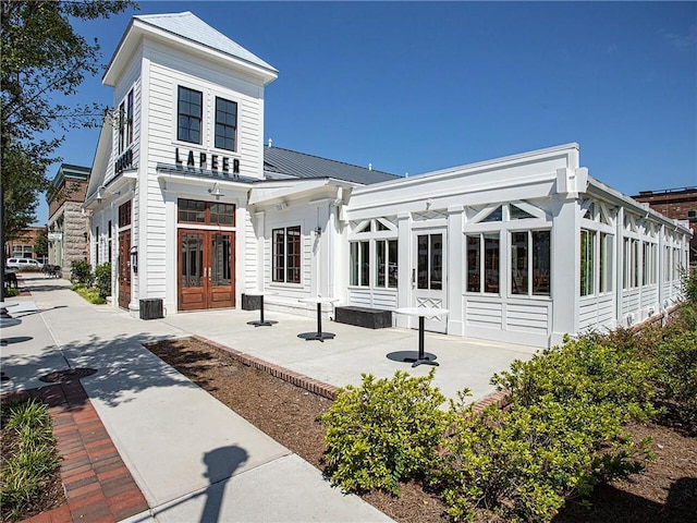 back of house with french doors, a patio, metal roof, and a sunroom