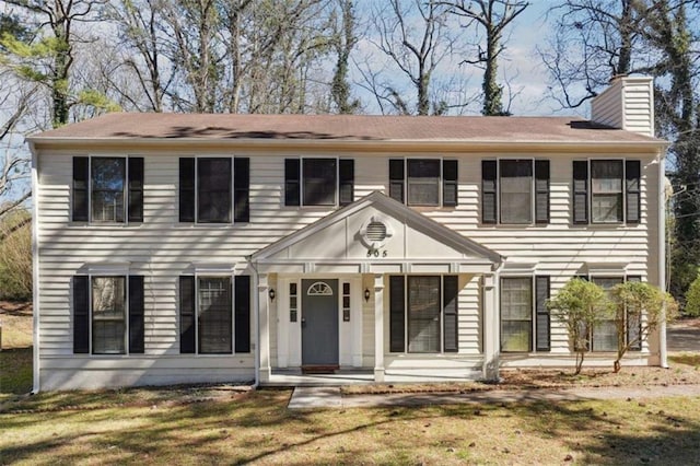 colonial house with a front lawn, a chimney, and a porch