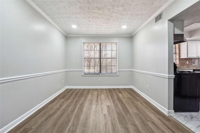 unfurnished dining area featuring visible vents, baseboards, a textured ceiling, and ornamental molding