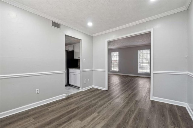 empty room with dark wood-style floors, baseboards, a textured ceiling, and ornamental molding