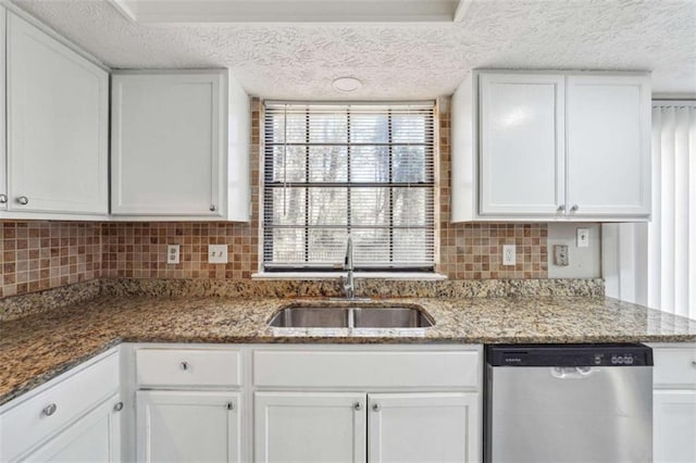 kitchen featuring stainless steel dishwasher, backsplash, a sink, and white cabinets