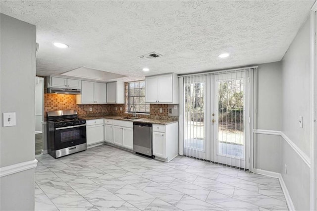 kitchen featuring under cabinet range hood, stainless steel appliances, a sink, marble finish floor, and decorative backsplash