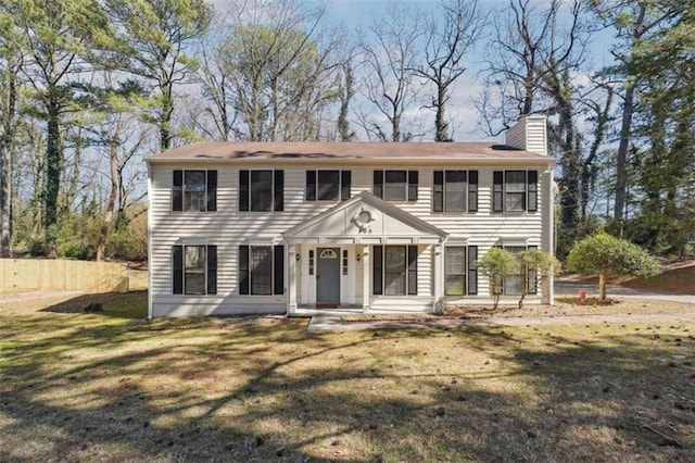 colonial house featuring a chimney and a front yard