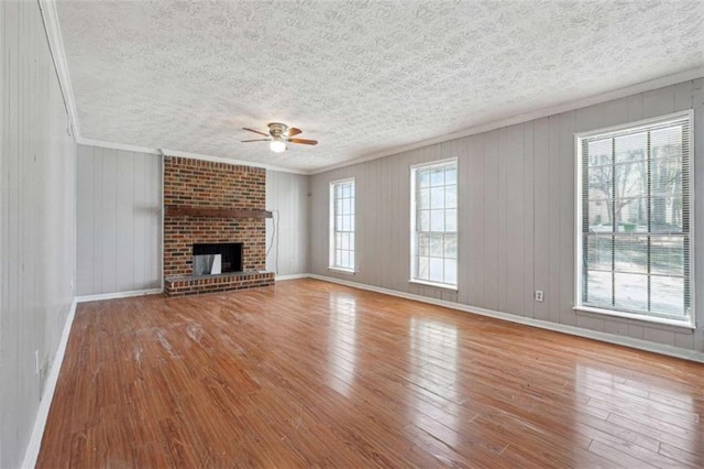 unfurnished living room featuring ornamental molding, a brick fireplace, ceiling fan, and hardwood / wood-style flooring