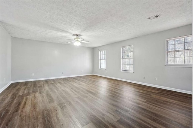 unfurnished room with visible vents, dark wood finished floors, and baseboards