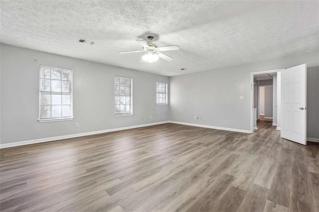 spare room with baseboards, visible vents, ceiling fan, and wood finished floors