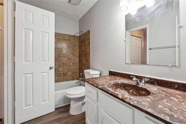 full bath featuring shower / bath combination, toilet, vanity, a textured ceiling, and wood finished floors