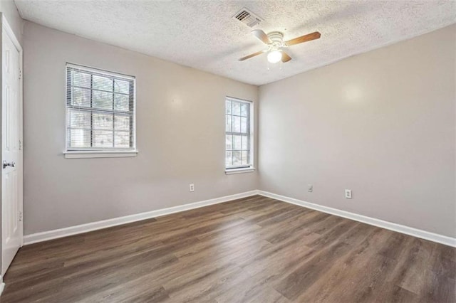 empty room featuring baseboards, visible vents, a ceiling fan, wood finished floors, and a textured ceiling