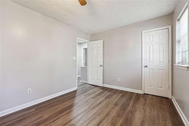 unfurnished bedroom featuring a textured ceiling, baseboards, and wood finished floors