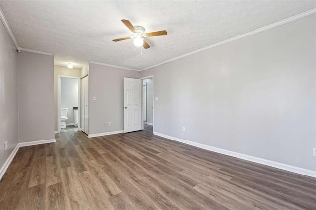 empty room with baseboards, a textured ceiling, wood finished floors, and crown molding