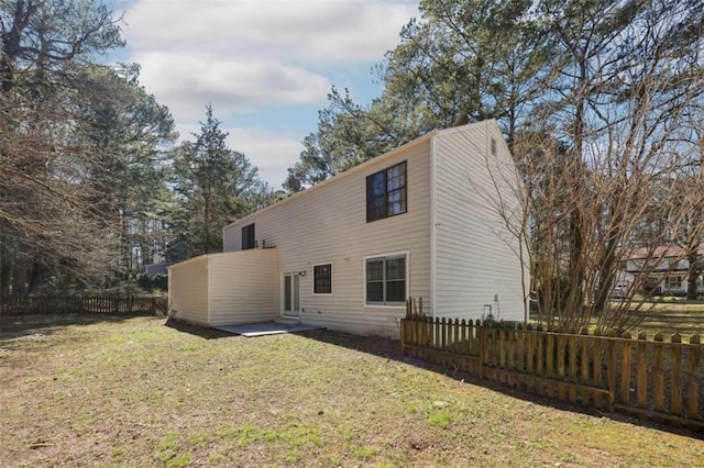 back of property featuring a lawn and fence