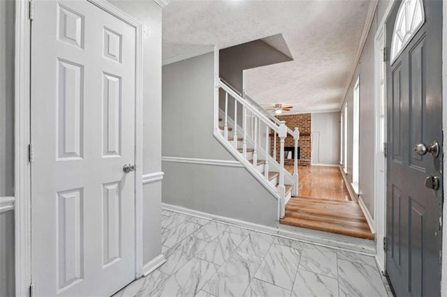 foyer featuring marble finish floor, baseboards, stairway, and a textured ceiling