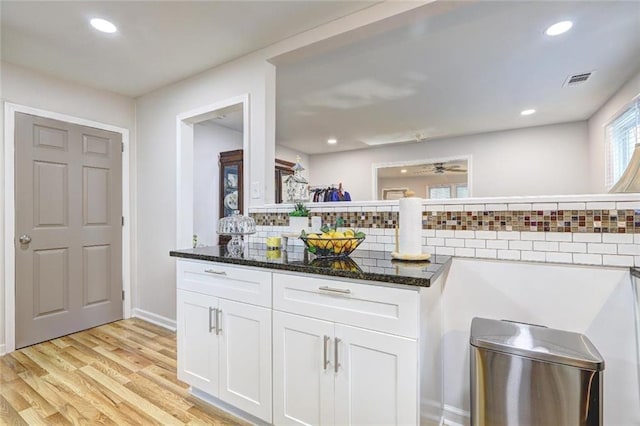 kitchen with dark stone counters, decorative backsplash, light hardwood / wood-style floors, and white cabinets