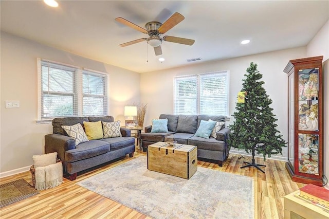 living room featuring light hardwood / wood-style flooring, ceiling fan, and a healthy amount of sunlight