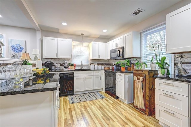 kitchen featuring hanging light fixtures, tasteful backsplash, white cabinets, black appliances, and sink