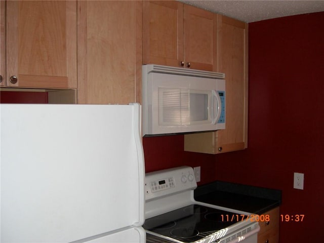 kitchen with a textured ceiling and white appliances