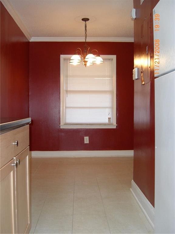 unfurnished dining area featuring crown molding and a chandelier