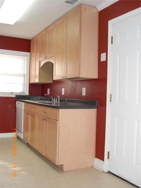 kitchen featuring sink, light tile patterned floors, light brown cabinetry, and white dishwasher