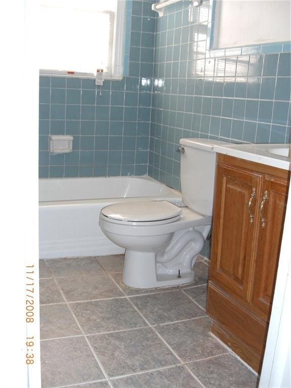 full bathroom with vanity, tub / shower combination, tile walls, and toilet