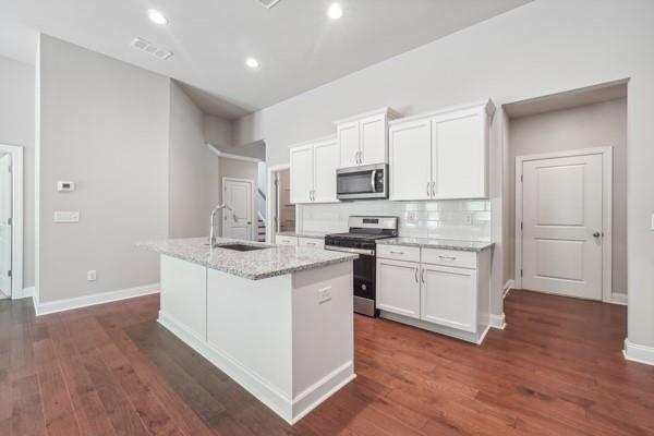 kitchen with a kitchen island with sink, sink, white cabinets, and appliances with stainless steel finishes