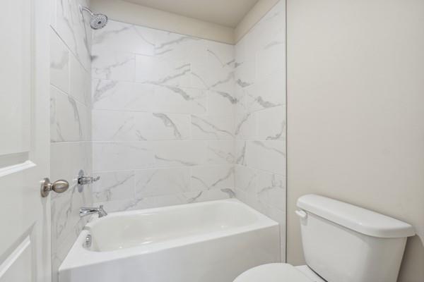 full bathroom featuring vanity, tiled shower / bath, and toilet