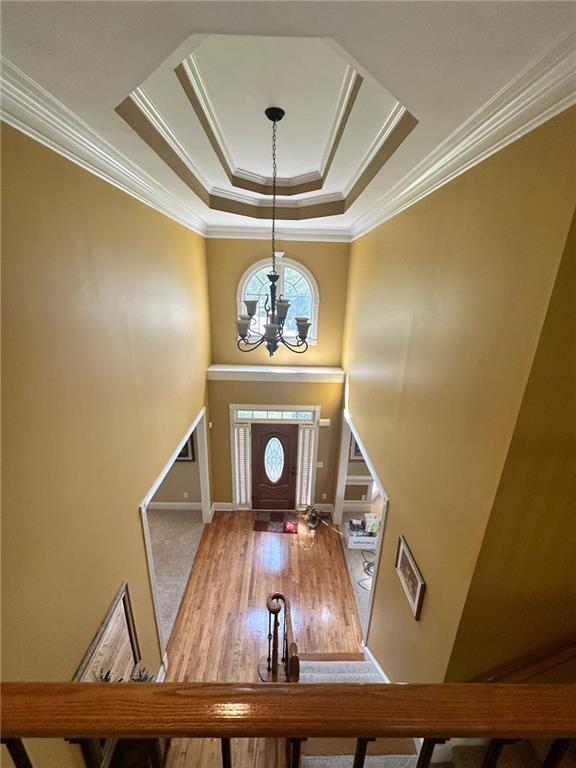 foyer with a raised ceiling, crown molding, and an inviting chandelier