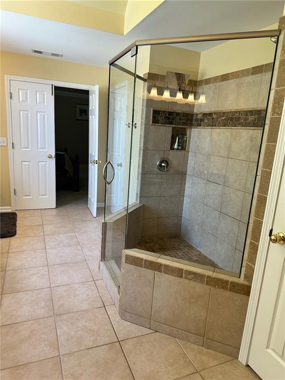 bathroom with tile patterned flooring and a shower with shower door