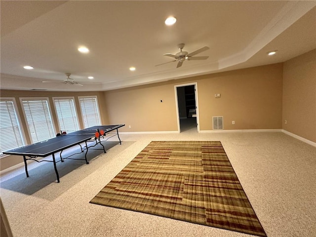 game room featuring ceiling fan, light colored carpet, and a tray ceiling