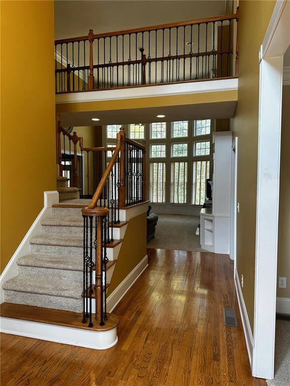 stairs featuring hardwood / wood-style floors and a towering ceiling