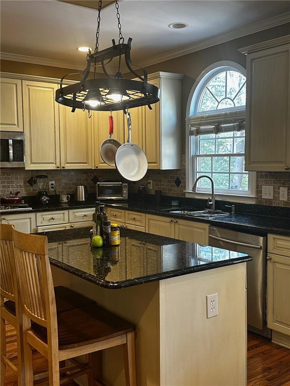 kitchen featuring sink, a center island, backsplash, pendant lighting, and appliances with stainless steel finishes