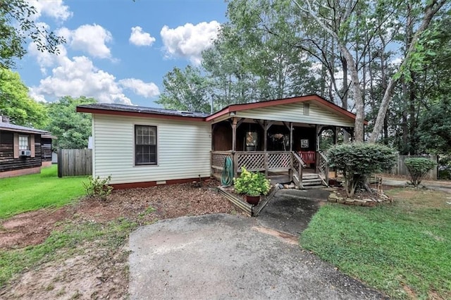 view of front of home with a porch, a front yard, crawl space, and fence