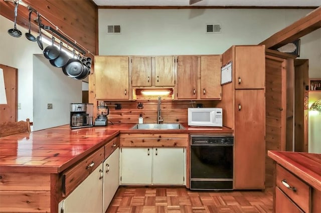 kitchen featuring black dishwasher, visible vents, a high ceiling, white microwave, and a sink