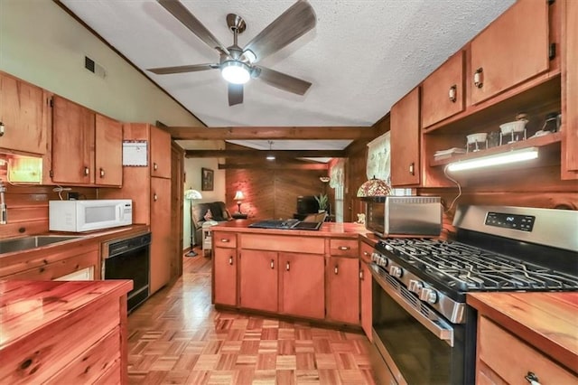 kitchen featuring visible vents, white microwave, wooden walls, wood counters, and stainless steel gas range oven