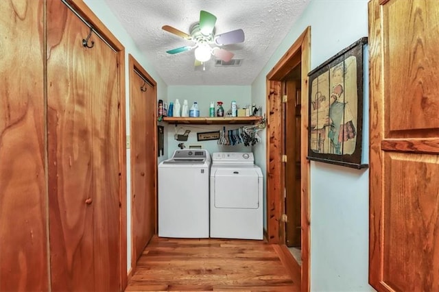 laundry area with a textured ceiling, ceiling fan, wood finished floors, visible vents, and independent washer and dryer