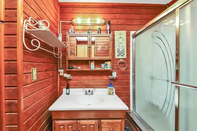 bathroom featuring wood walls, vanity, and a shower with shower door